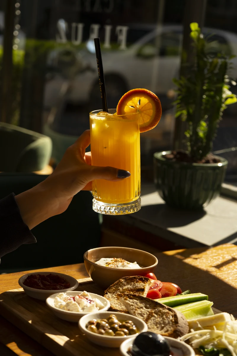 An orange drink and breakfast plates in the sun